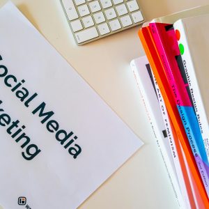 A top view of social media marketing text alongside graphic design books and a keyboard.
